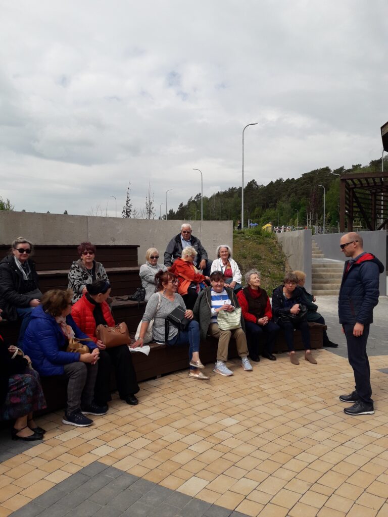 Pochmurne niebo, siedząca grupa ludzi na schodkach każdy obraca się w inną stronę