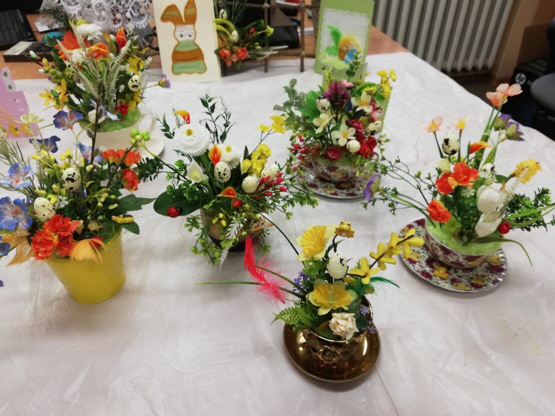 Na stole stoi rozstawionych 6 filiżanek z bukietami kwiatów w środku.