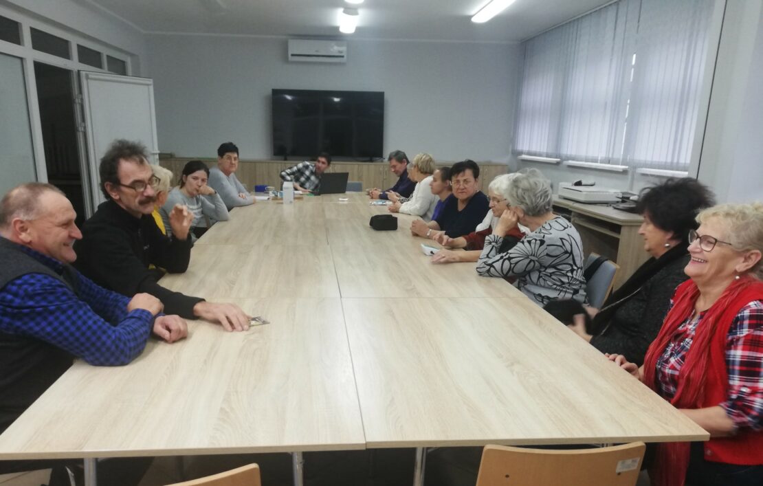 Uczestnicy spotkania siedzą przy dużym stole. Czekaja na prezentację sprzętu.