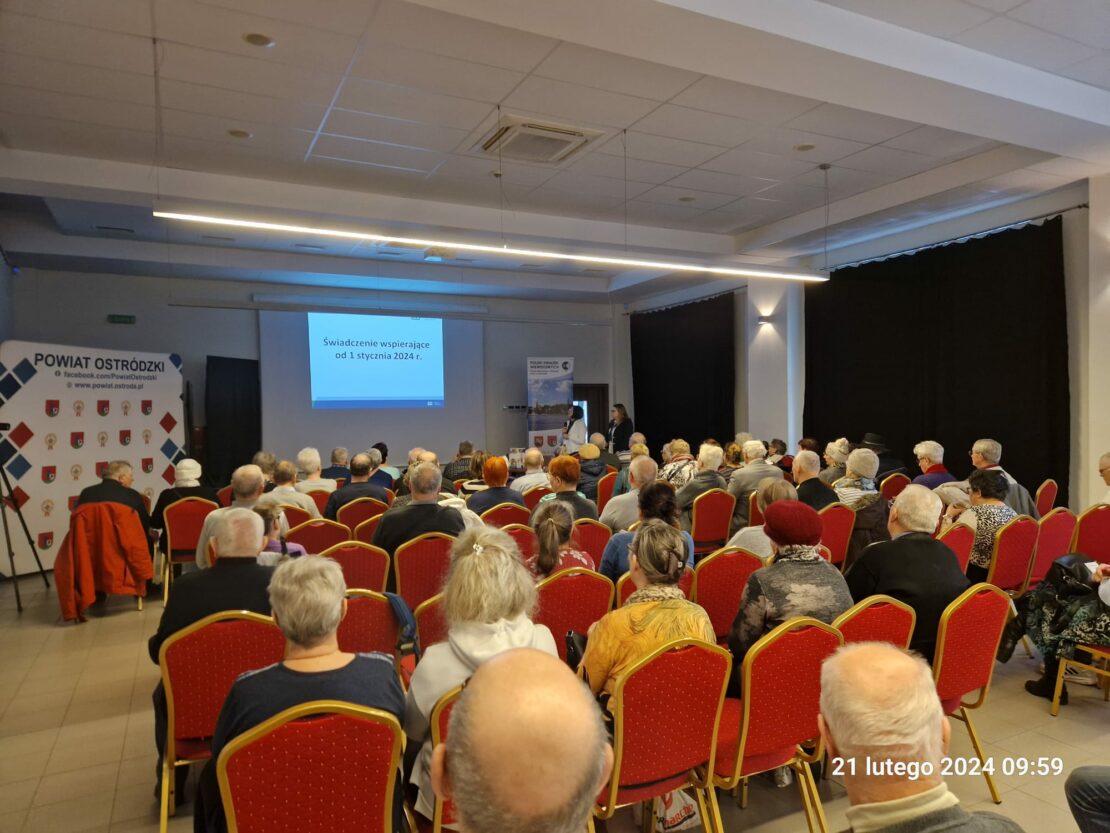 Widok na salę. Na krzesłach siedzą uczestnicy spotkania na scenie Panie z ZUSu opowiadają o uprawnieniach dla osób z niepełnosprawnością.